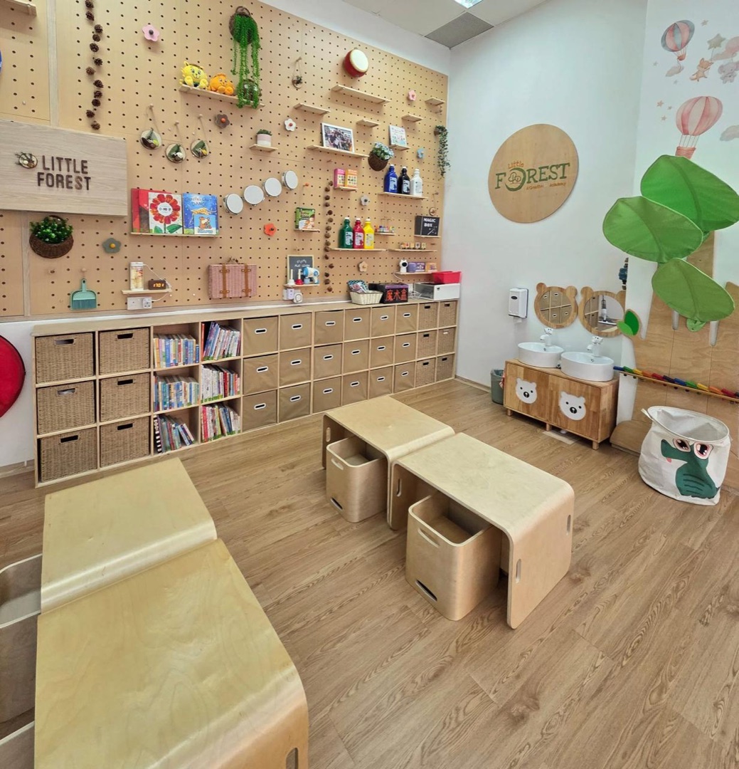 The Kovan classroom, with a pegboard wall of books and materials, low wooden tables and child-height sinks
